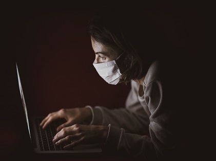 woman sitting laptop computer face mask